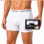 Homem vestindo a cueca boxer Tudo Fluy branca, segurando a caixa do kit