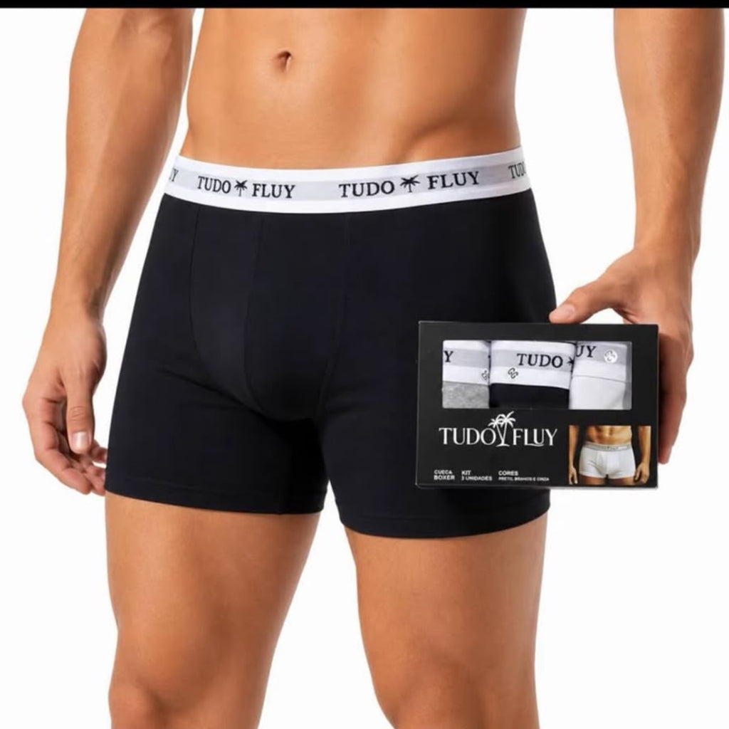 Homem vestindo a cueca boxer Tudo Fluy preta, segurando a caixa do kit
