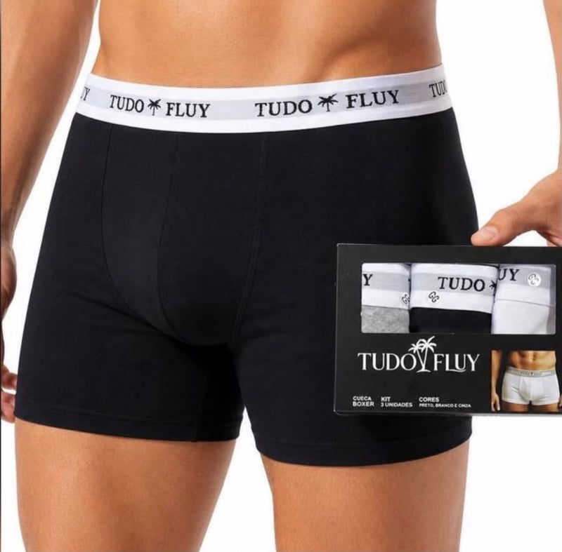 Cueca boxer preta vestida, ao lado da caixa do kit com 3 unidades