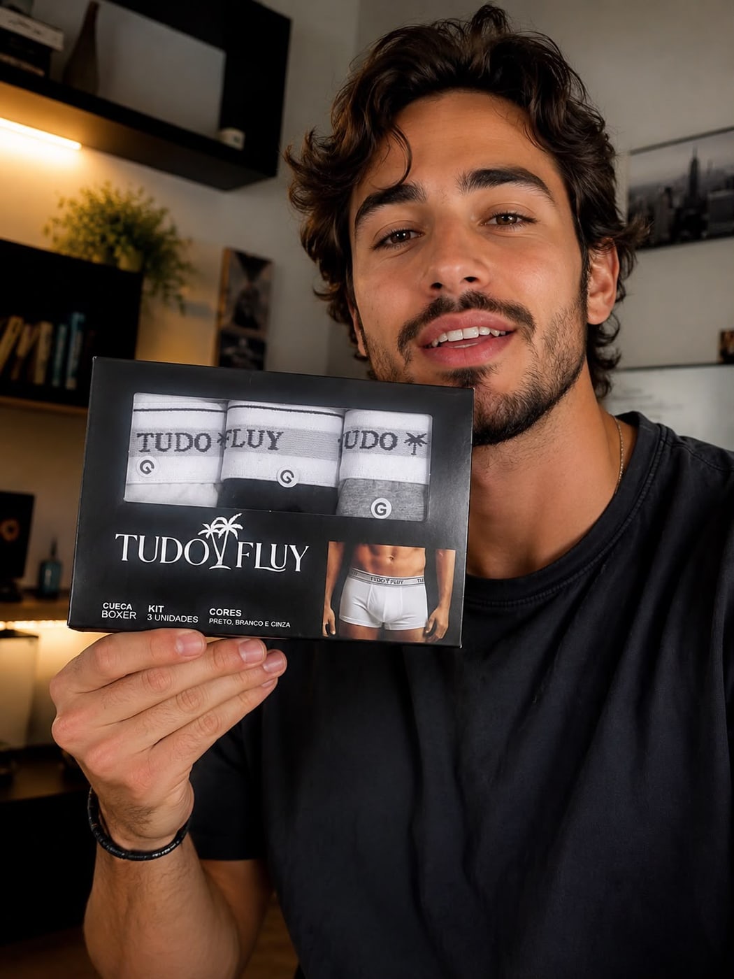 Homem sorrindo com a caixa do Kit 3 de cuecas boxer Tudo Fluy